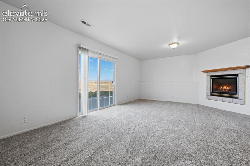 Image 25 of 46: Carpeted living space featuring a fireplace with a tile surround and wood m