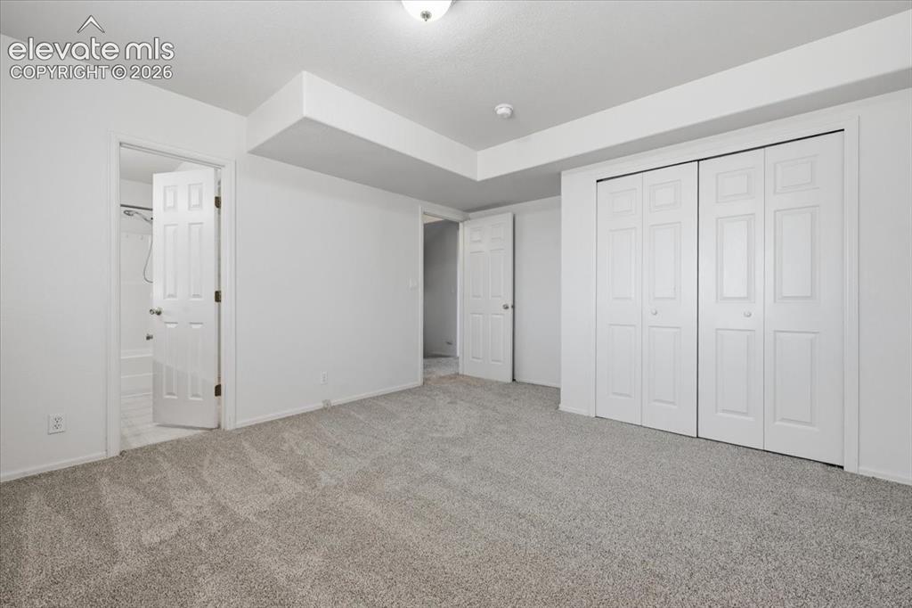 Image 28 of 46: Plush carpeted flooring, bi-fold closet doors, white paneled doors, and cei
