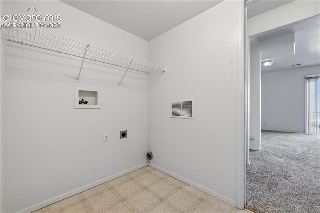 Image 30 of 46: Laundry area featuring wire shelving, utility hookups, and tiled flooring