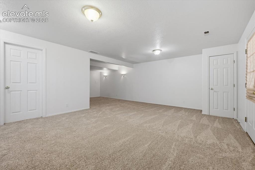 Image 32 of 46: Expansive carpeted area with neutral walls and multiple panel doors