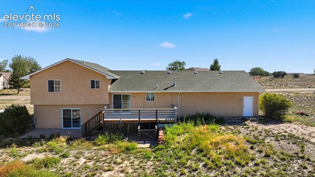 Image 39 of 46: Rear exterior with a multi-level deck, multiple sliding glass doors, and a 
