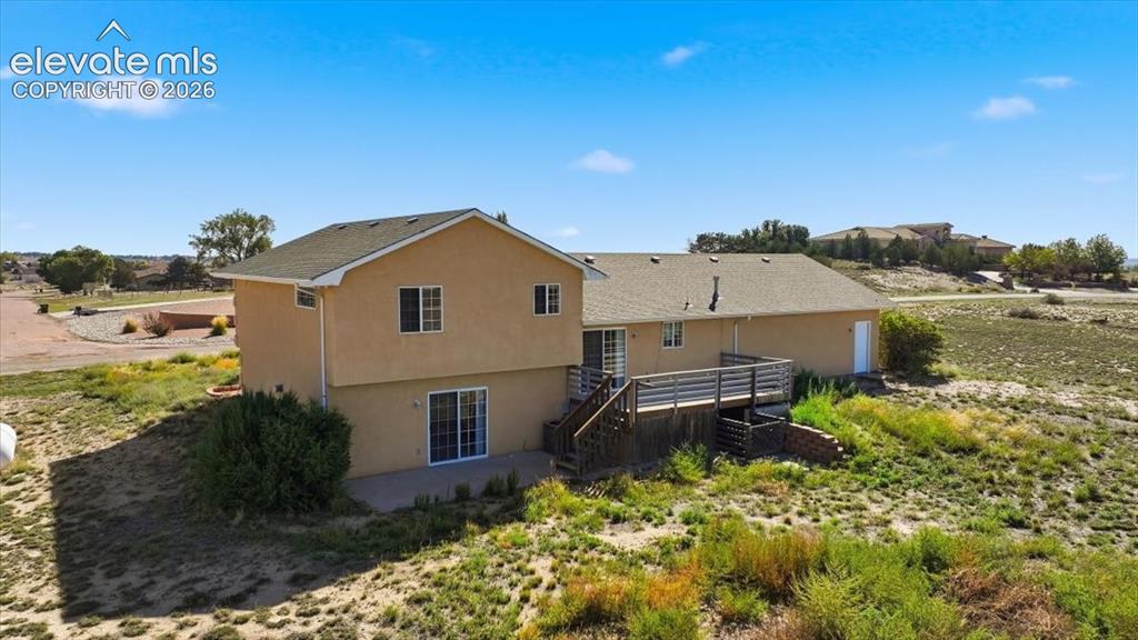 Image 40 of 46: Stucco exterior with a multi-level deck featuring wood railings, a ground-l