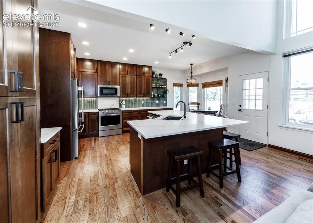 Image 10 of 38: Expansive kitchen featuring wood-finish flooring, dark wood cabinetry, a la