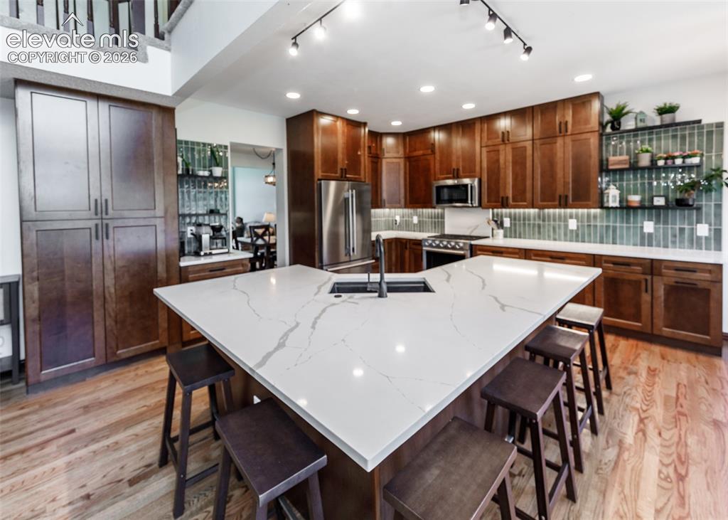 Image 11 of 38: Kitchen featuring a large island with white stone-finish countertop, wood-f
