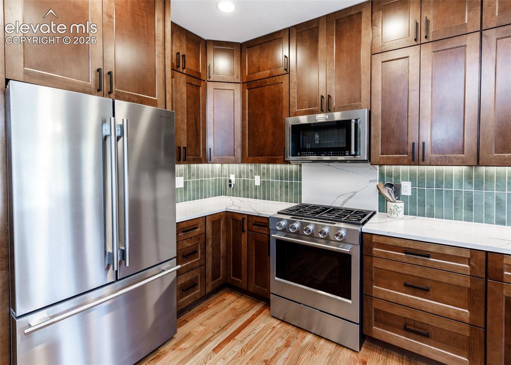 Image 12 of 38: Stainless steel appliances, wood-finish flooring, white countertops, tile b