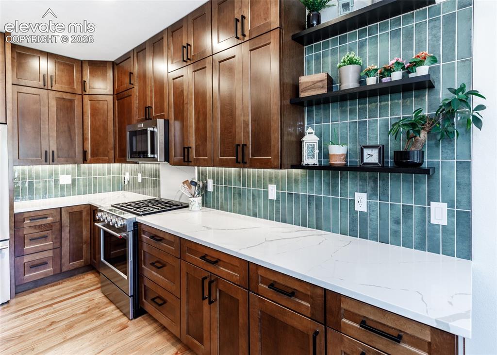 Image 13 of 38: Hardwood flooring, custom wood cabinetry, stainless steel appliances, white