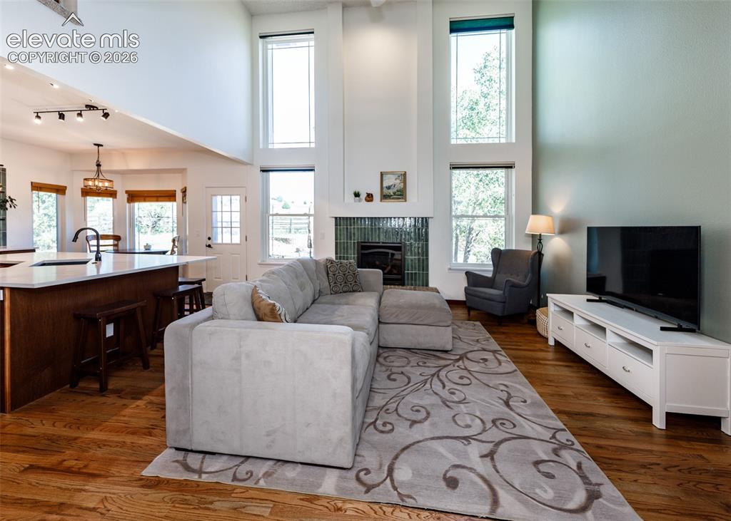 Image 15 of 38: Vaulted ceilings, wood-finish flooring, a kitchen island with seating, a fi