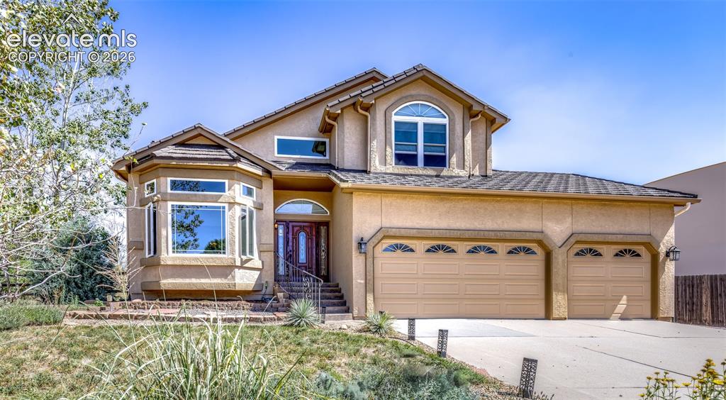 Image 2 of 38: Stucco exterior with a multi-level roofline, arched entry, bay window with