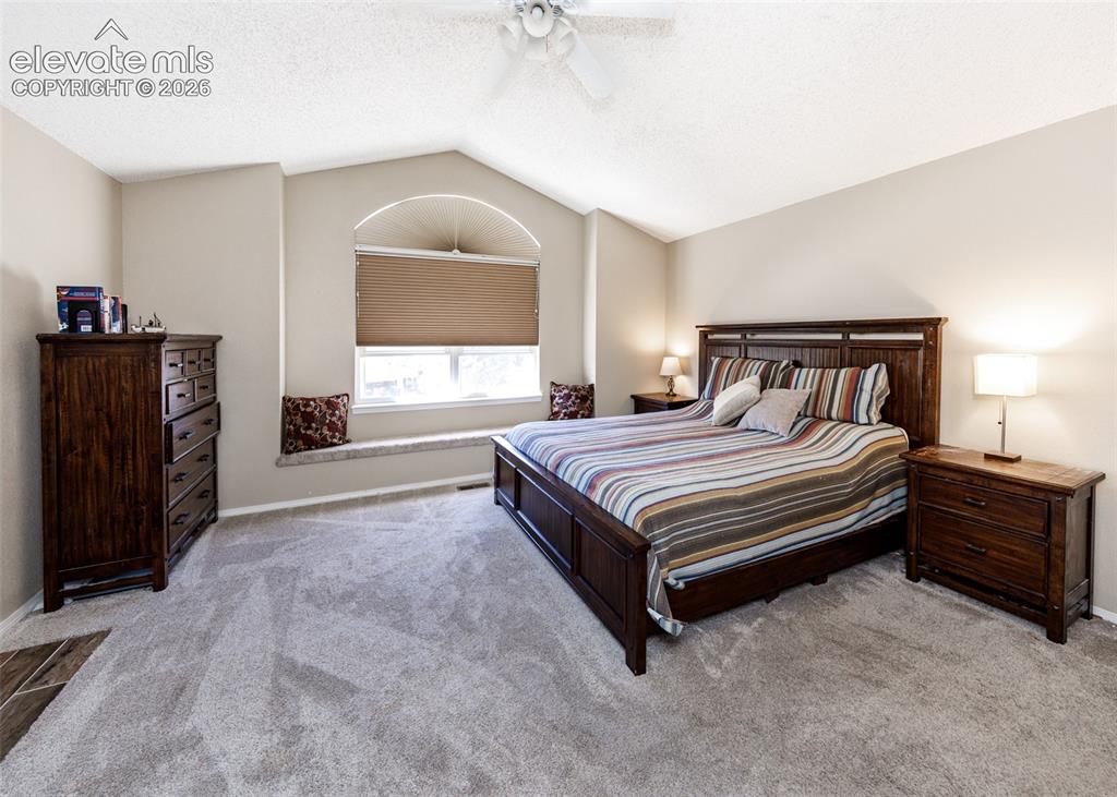 Image 20 of 38: Vaulted ceiling with a ceiling fan, arched window with a window seat, and c