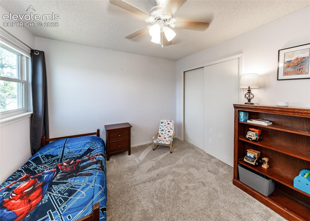 Image 26 of 38: Textured carpet flooring, window with sash, ceiling fan with light fixture,