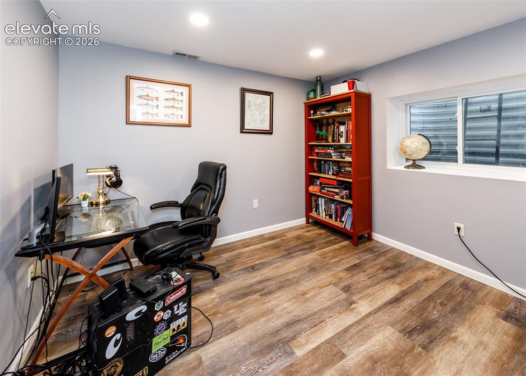 Image 29 of 38: Wood-finish flooring, recessed lighting, built-in shelving, a large window,