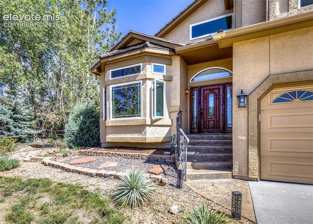 Image 4 of 38: Stucco exterior with a prominent bay window, an ornate wood-finish entry do