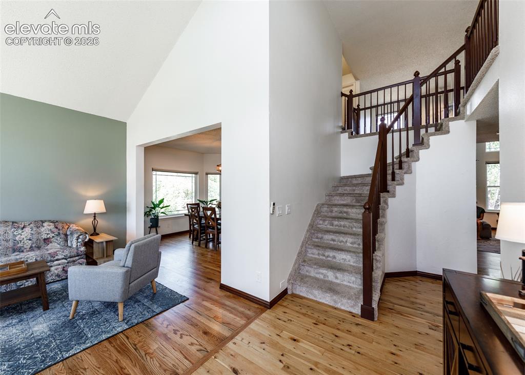 Image 5 of 38: Vaulted ceiling, wood-finish flooring, carpeted staircase with wood baniste