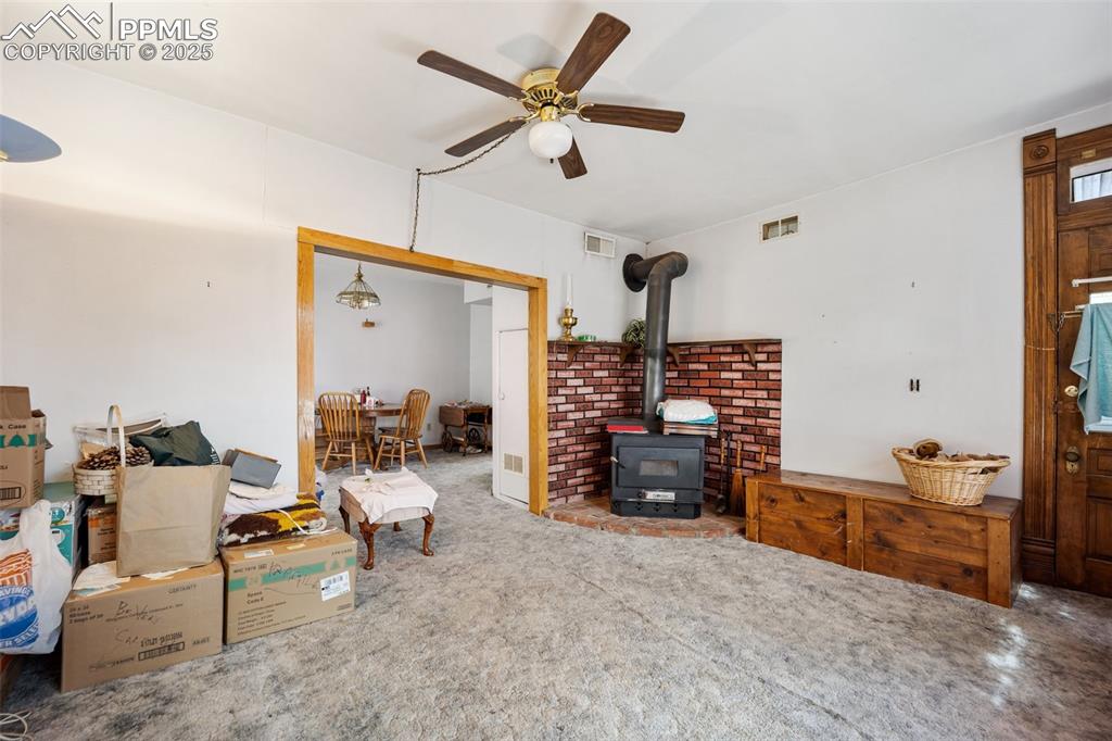 Image 10 of 48: Carpeted living area featuring a wood stove and ceiling fan