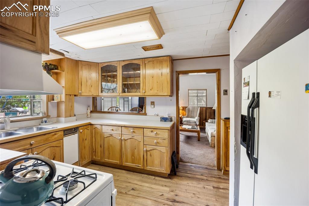 Image 18 of 48: Kitchen with white gas range, light wood-style flooring, light countertops,