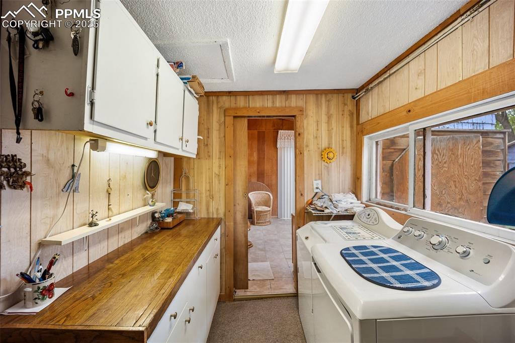 Image 19 of 48: Laundry area with wood walls, cabinet space, washer and clothes dryer, and 