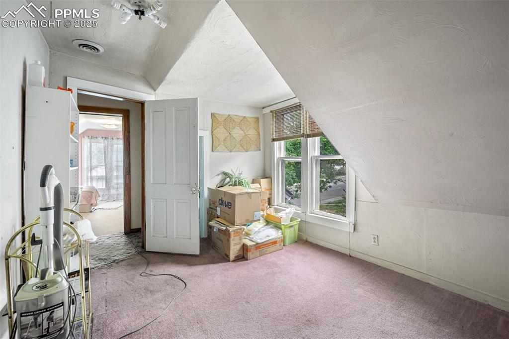 Image 29 of 48: Additional living space with carpet floors, a textured ceiling, and vaulted
