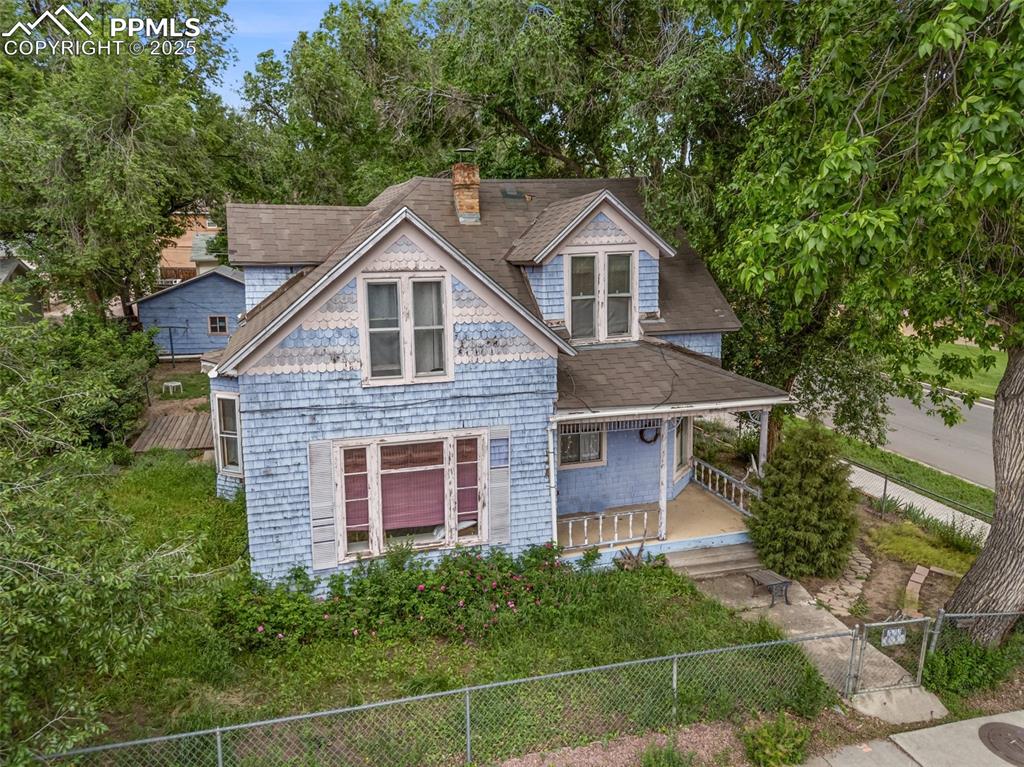 Image 33 of 48: Victorian home featuring a porch, a chimney, a fenced backyard, roof with s
