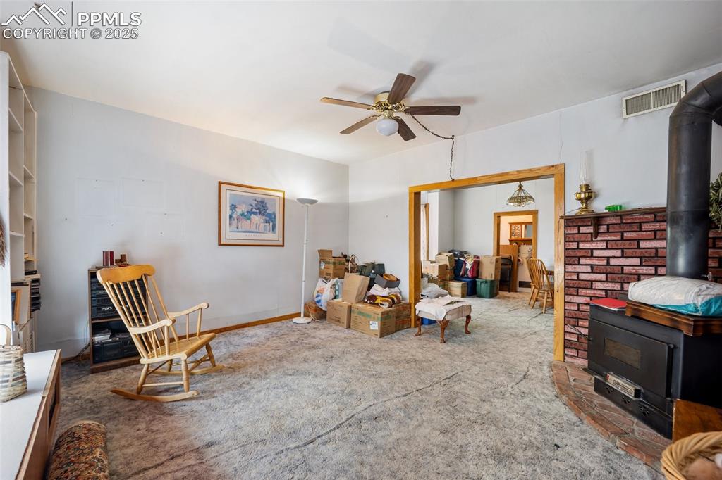 Image 8 of 48: Sitting room with a wood stove, a ceiling fan, and carpet