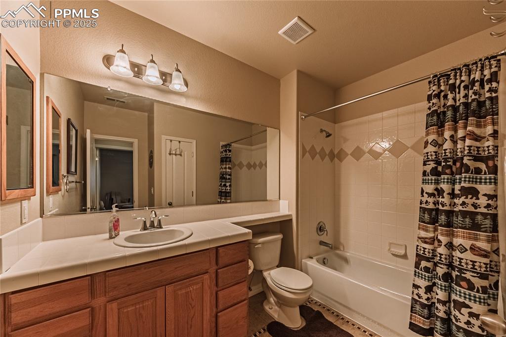 Image 33 of 50: Bathroom with visible vents, toilet, shower / tub combo with curtain, a tex