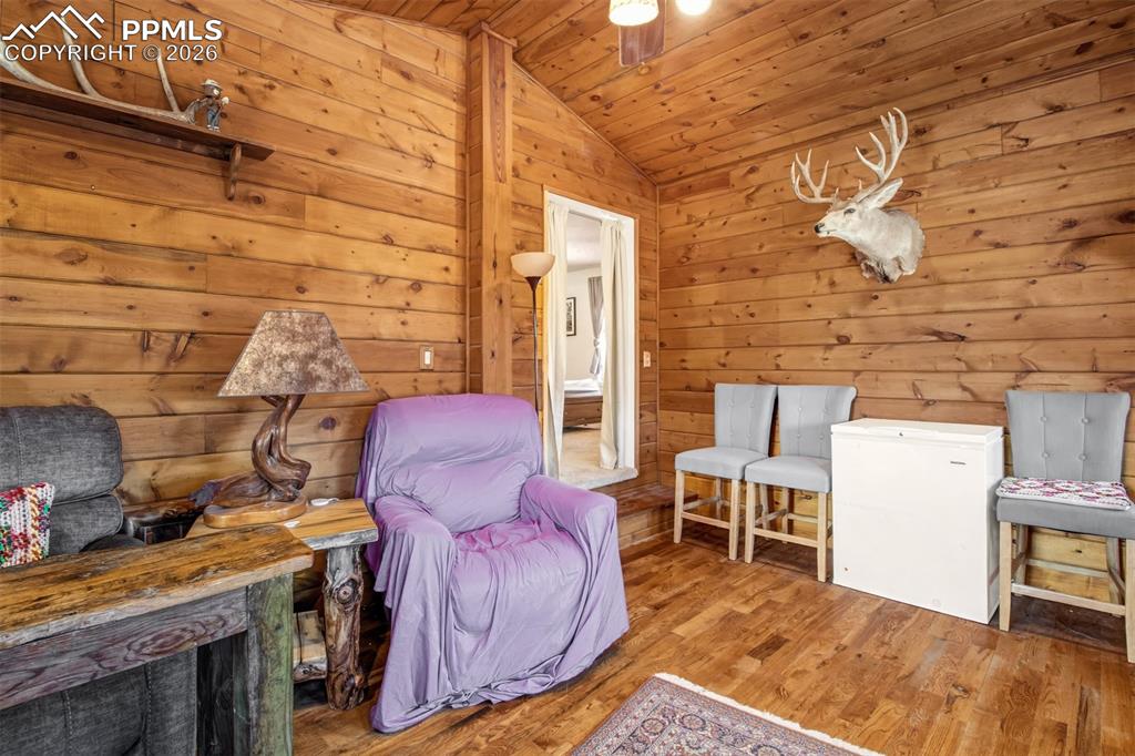 Image 19 of 38: Sitting room off primary with gas burning stove, wood floors and wood accen