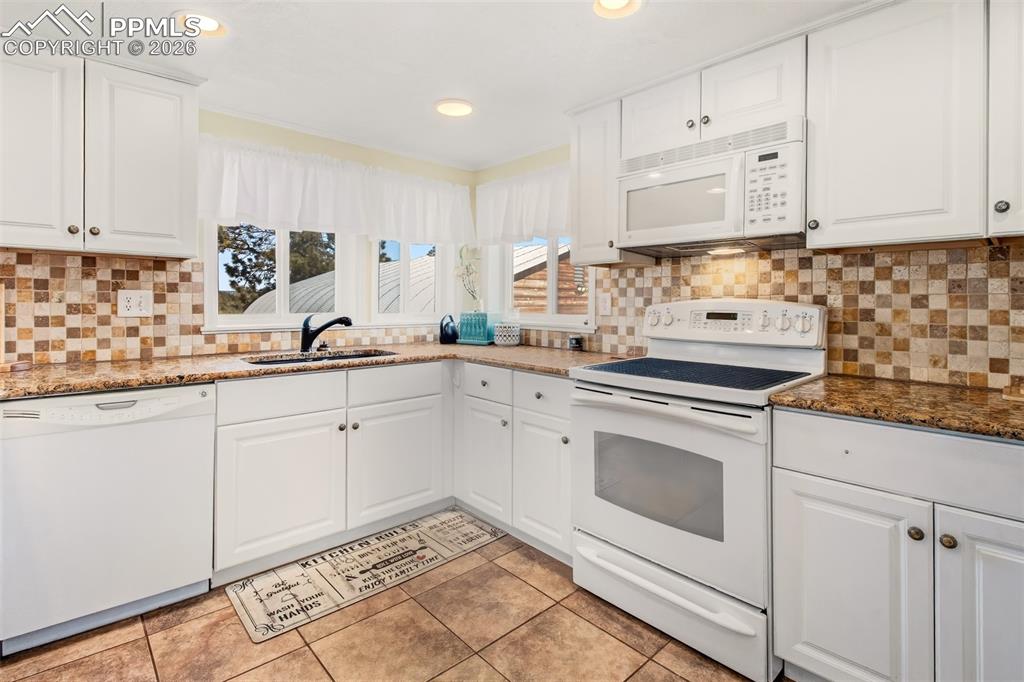 Image 8 of 38: Kitchen with granite counter tops, matching white cabinetry and appliances,