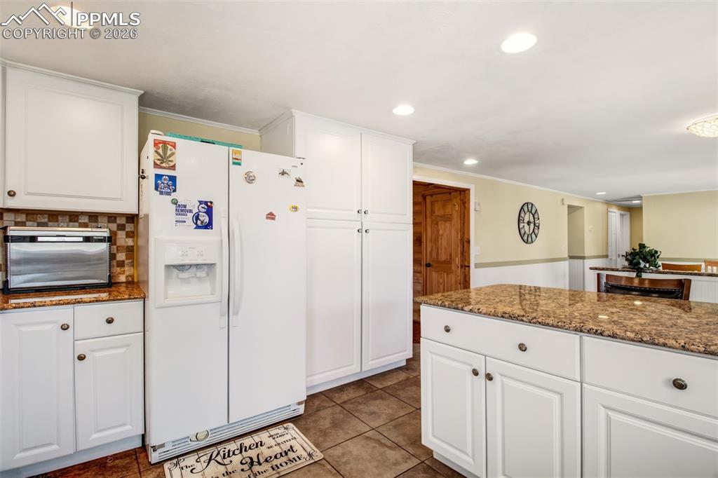 Image 9 of 38: Kitchen with granite counter tops, matching white cabinetry and appliances,
