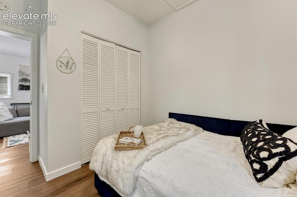 Image 10 of 25: Wood-finish flooring, white louvered bifold closet doors, and white painted