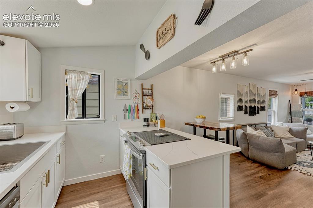 Image 11 of 21: Modern kitchen featuring white cabinetry, quartz countertops, and stainless