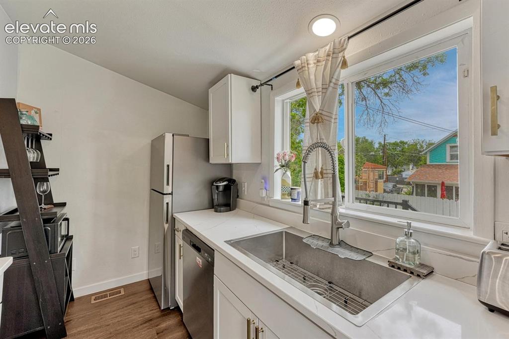 Image 12 of 21: Kitchen featuring white shaker cabinetry, stainless steel appliances, a dee