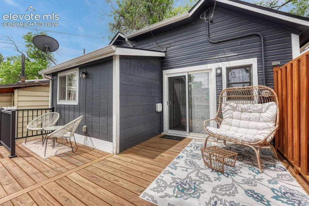 Image 15 of 21: Expansive wood deck with a dark gray exterior, white trim, sliding glass do