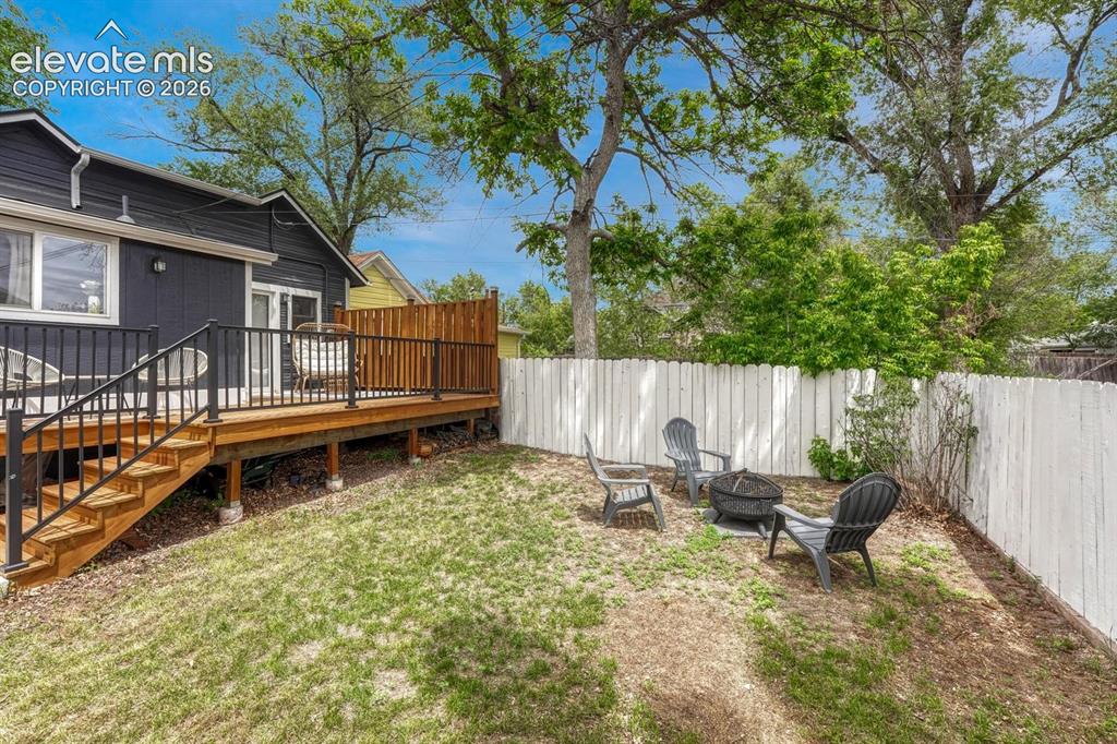Image 16 of 21: Private backyard featuring a wood deck with black metal railings, a white p