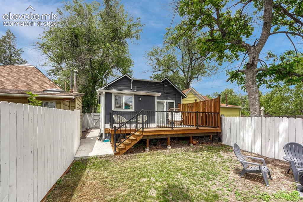 Image 17 of 21: Rear exterior featuring a spacious wood deck with black metal railings and