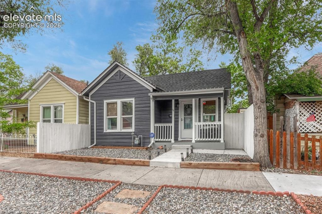 Image 2 of 21: Charming bungalow featuring dark gray horizontal siding with white trim, a