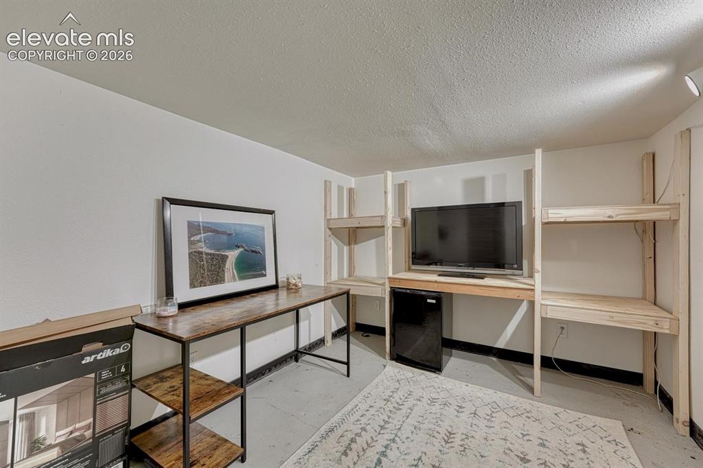 Image 20 of 21: Custom-built wood shelving and desk system provides integrated storage and