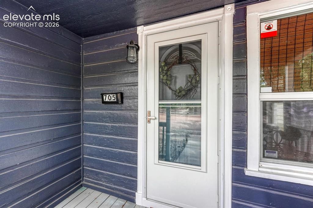 Image 4 of 21: Front entry featuring a white storm door with glass paneling, dark blue hor