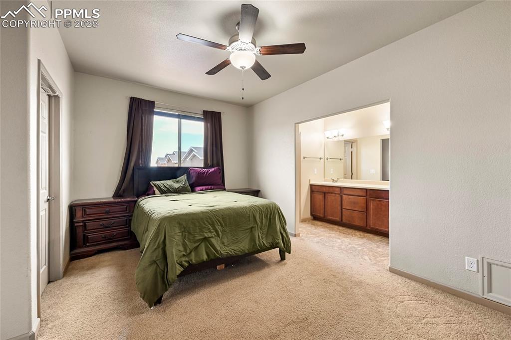 Image 10 of 22: Bedroom with ensuite bath, a ceiling fan, baseboards, and light carpet