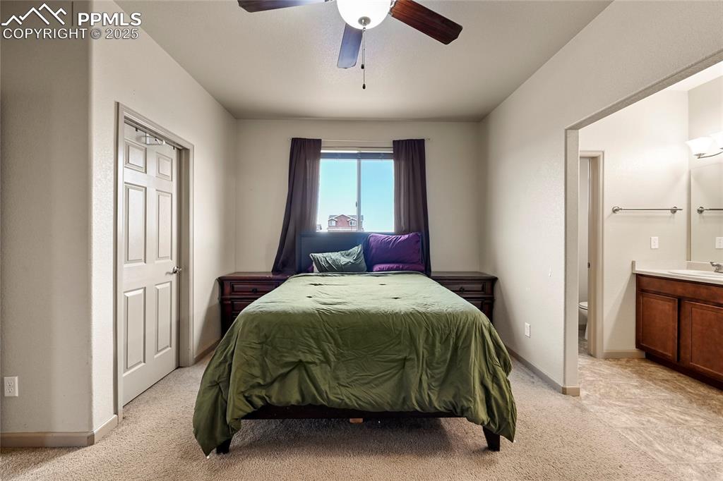 Image 11 of 22: Bedroom with a sink, baseboards, light colored carpet, ceiling fan, and ens