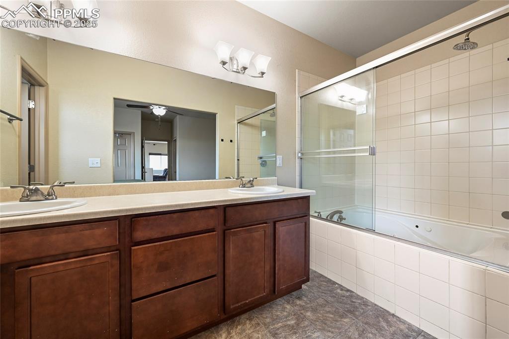 Image 13 of 22: Bathroom featuring tiled shower / bath, double vanity, ceiling fan, and a s