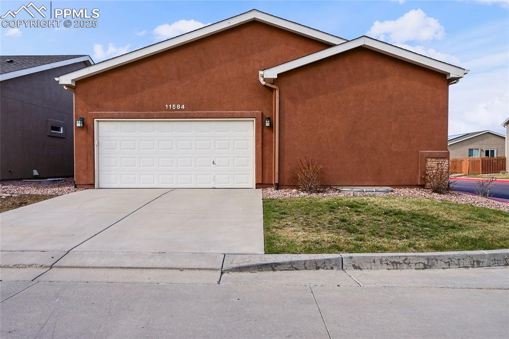 Image 2 of 22: Ranch-style house with a garage, a front lawn, stucco siding, and concrete
