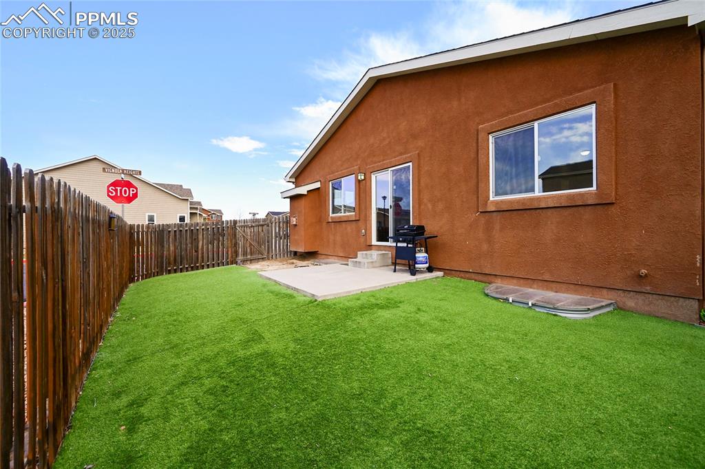 Image 22 of 22: Back of house featuring a yard, a fenced backyard, a patio, and stucco sidi