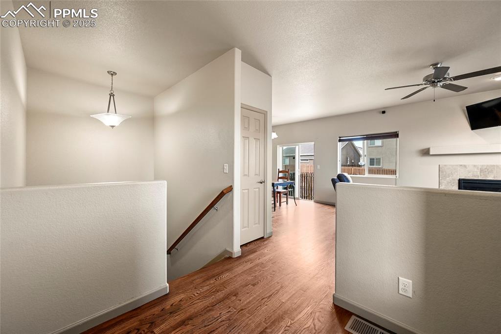Image 3 of 22: Hall with wood finished floors, a textured ceiling, and an upstairs landing