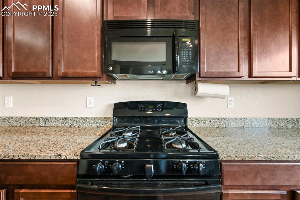 Image 7 of 22: Kitchen with black appliances and light stone countertops