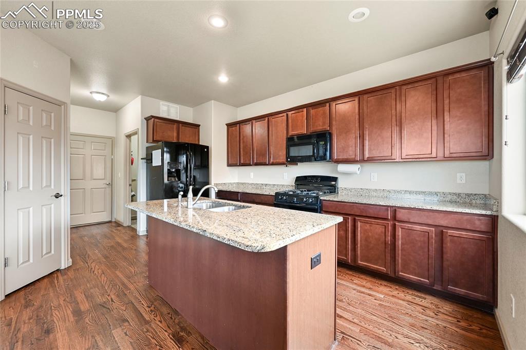 Image 8 of 22: Kitchen with a sink, dark wood finished floors, light stone counters, an is