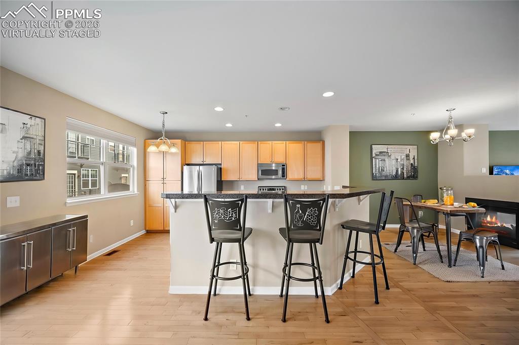 Image 9 of 49: virtually staged - 3-sided Fireplace for the kitchen area and living.