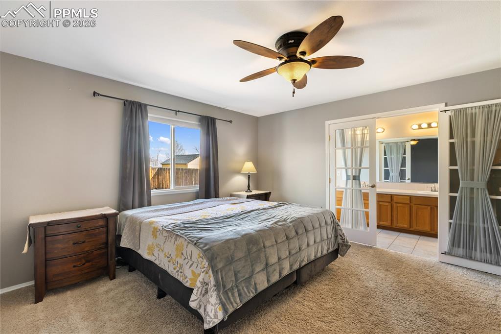 Image 19 of 36: Bedroom featuring light colored carpet, a ceiling fan, french doors, and en