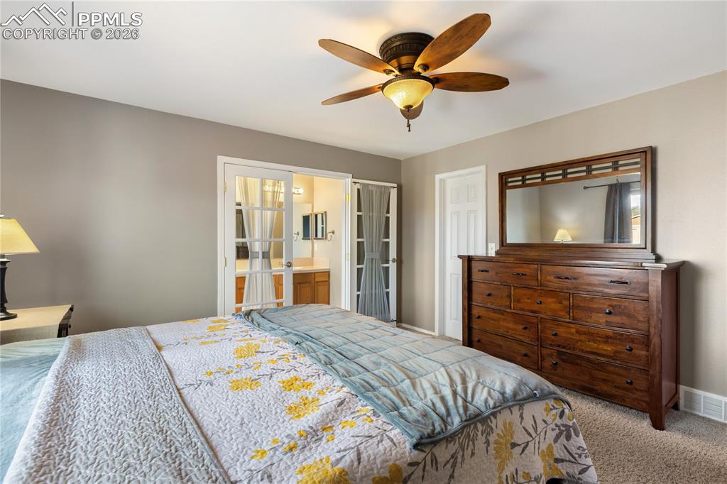 Image 20 of 36: Carpeted bedroom with a ceiling fan and ensuite bathroom