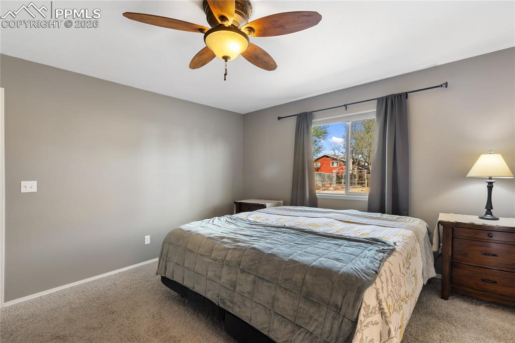 Image 21 of 36: Bedroom with ceiling fan and carpet floors