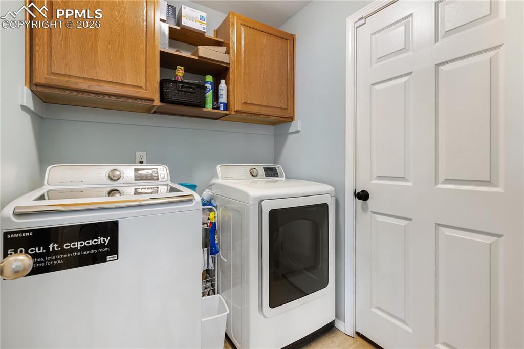 Image 24 of 36: Laundry area featuring independent washer and dryer and cabinet space