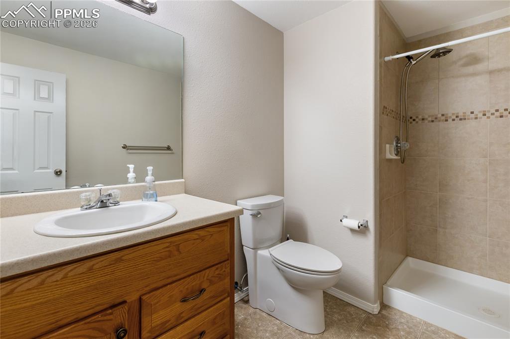Image 31 of 36: Full bath with vanity, a stall shower, light tile patterned flooring, and a
